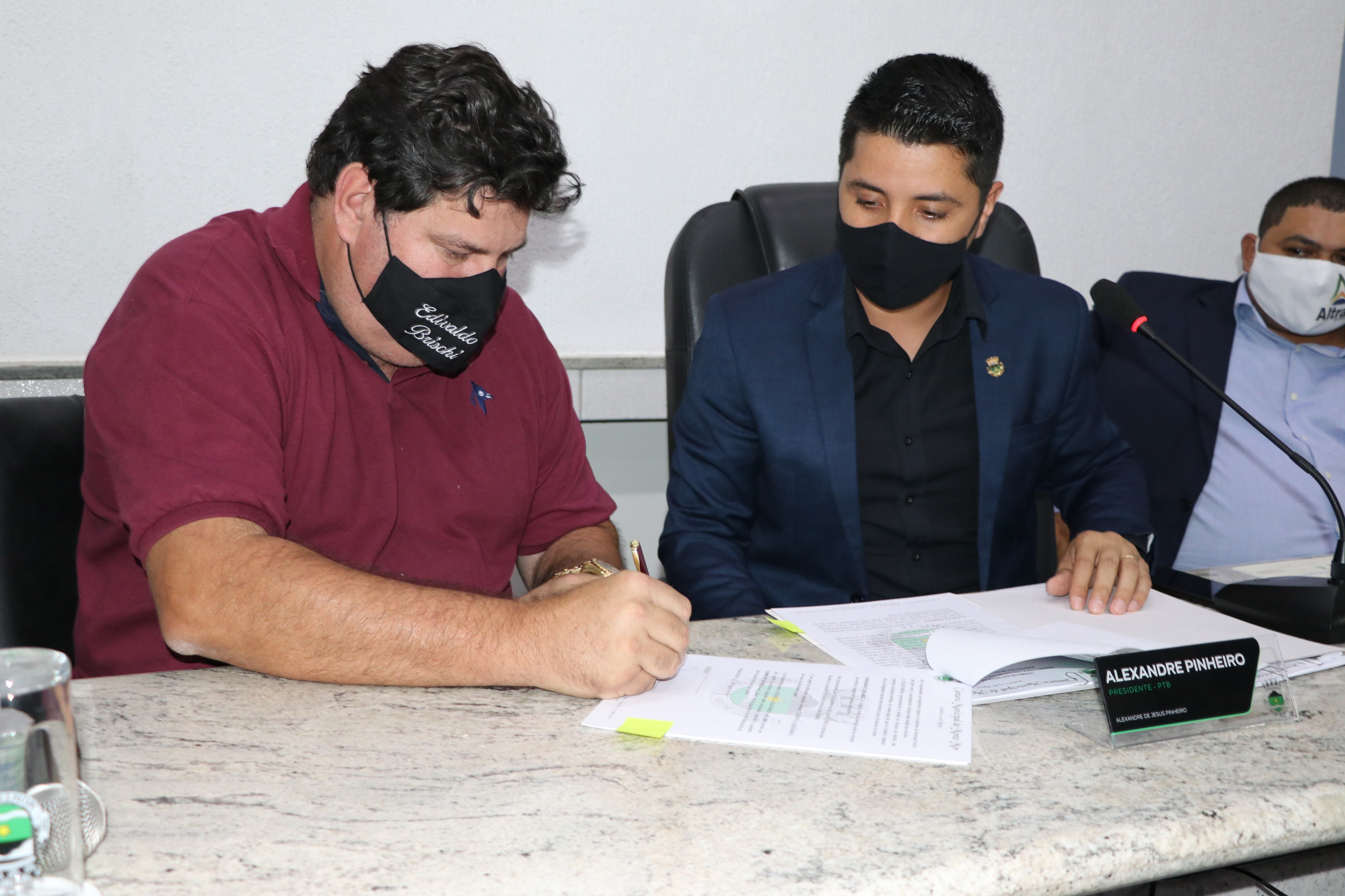 O prefeito Edivaldo Brischi assina o termo de entrega dos automóveis ao lado do presidente Alexandre e do vice presidente Altran